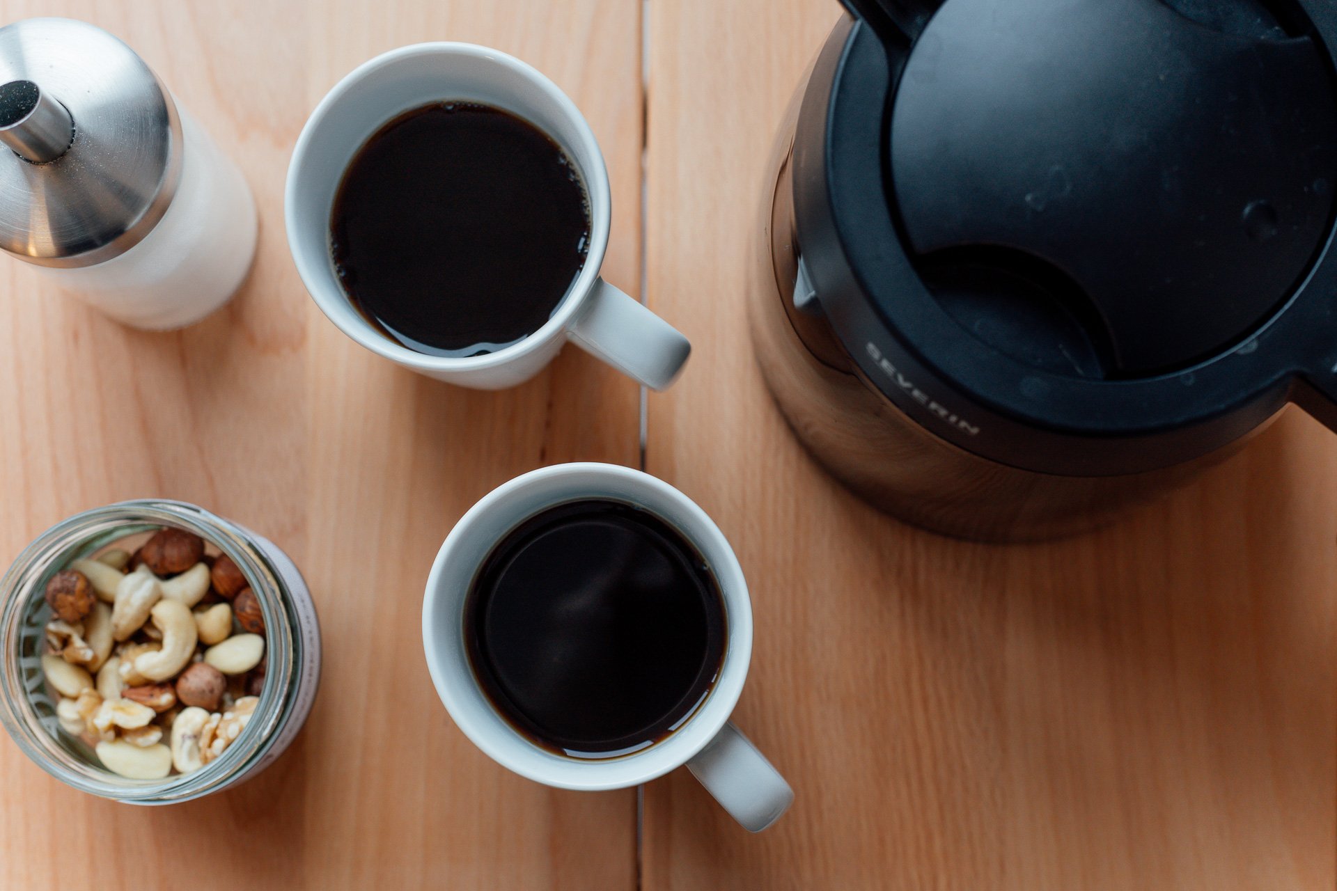 Zwei Tassen Kaffee mit Kaffeekanne und Nüssen